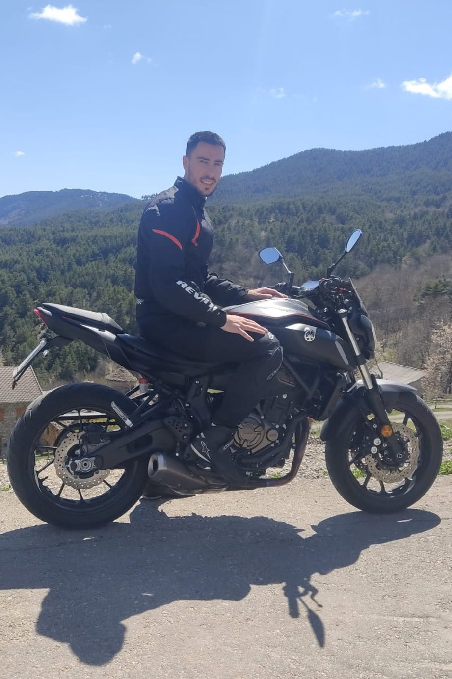 Daniel en su moto naked negra con montañas del Pirineo al fondo